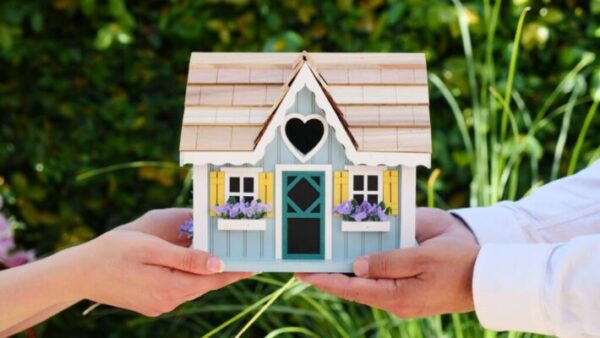 People holding a wooden miniature house