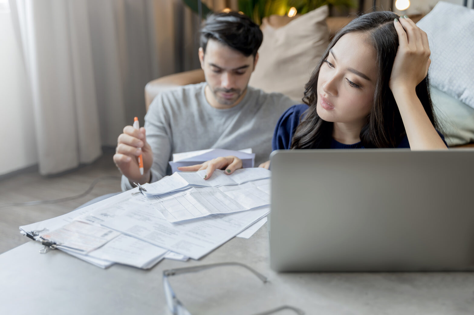 home finance,husband and wife discussing paper bill receipt together with stress and confused feeling with many problem and debt home interior background